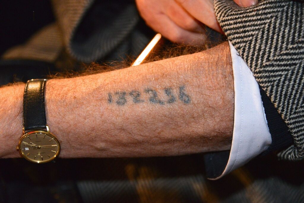 Holocaust survivor showing Auschwitz tattoo number on arm